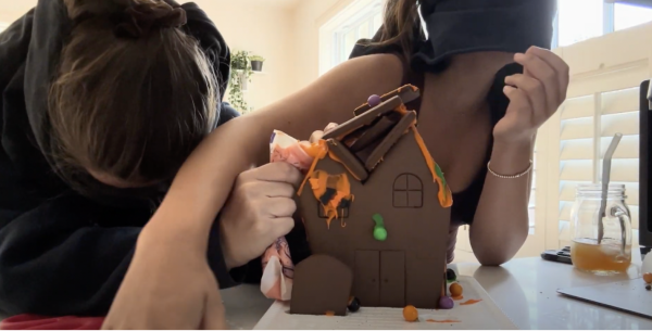 Siena Petrosinelli ’25 and Samantha Sandrew ’25 attempt to decorate a haunted halloween gingerbread house. To add extra challenge, they decided to blindfold themselves. The experiment turned out unsuccessful, with many participants leaving with frosting on their digits. 