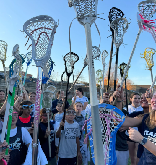 At Staples girls’ lacrosse Election Day clinic, everyone puts their sticks in the middle to end the clinic with a “one, two, three, Westport!” 